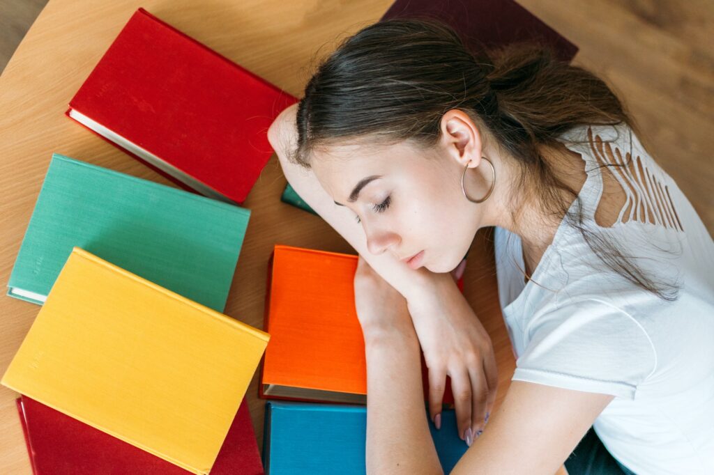 Tired student sleeping on book at library. Top view of female student sleeping at the desk with