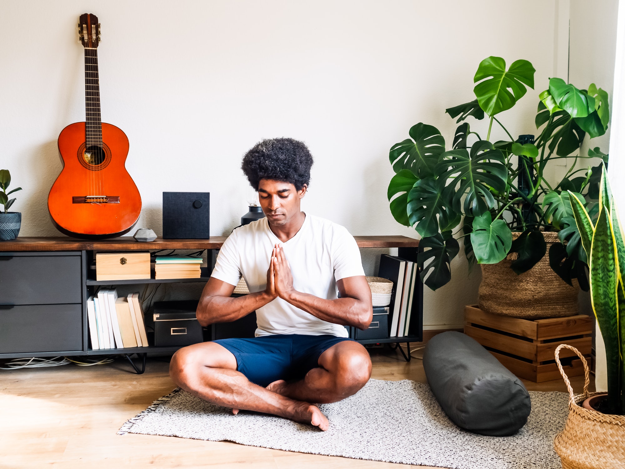 Young African American man doing yoga in an apartment