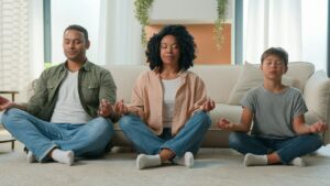 Calm peaceful multiracial family African American parents teach meditation son kid with closed eyes