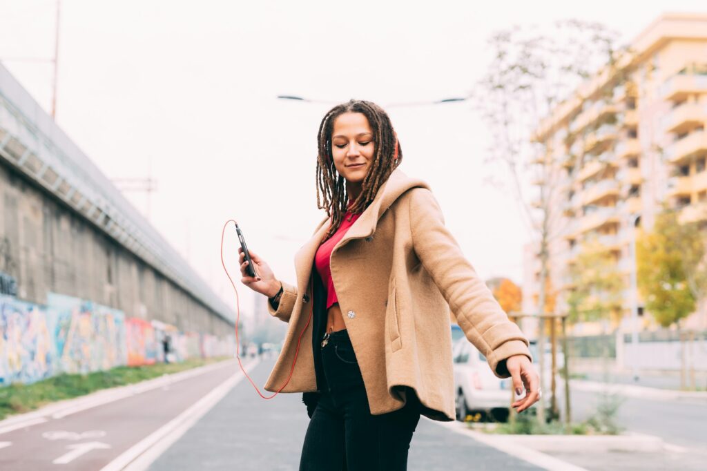 young woman outdoors dancing listening music