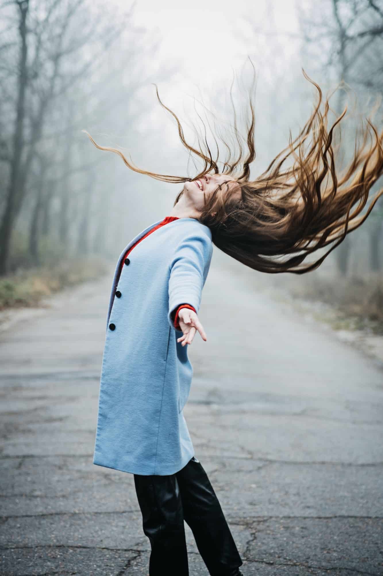 Alone Young woman with long fluttering hair express emotions in forest