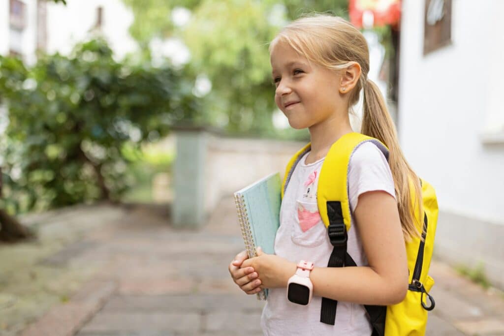 Schoolgirl back to school after summer vacations. Happy Child smiling early morning outdoor.