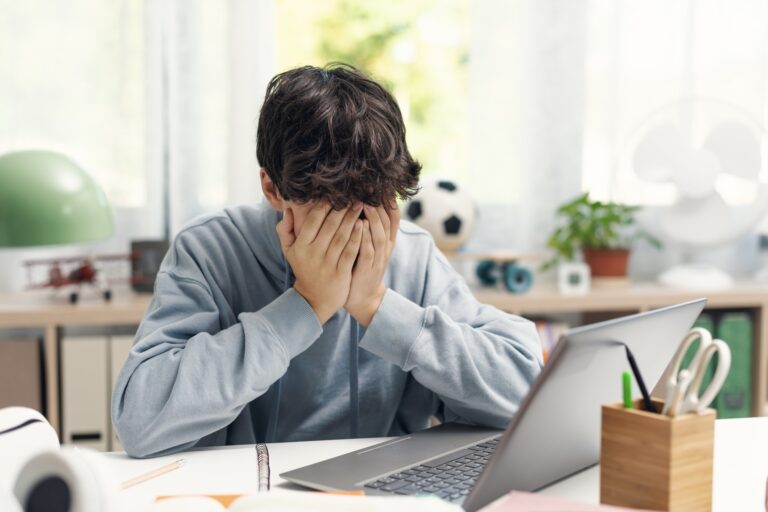 Exhausted student resting with head in hands
